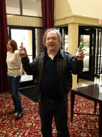 ESR holding a red and a green bottle of ACME hot sauce.